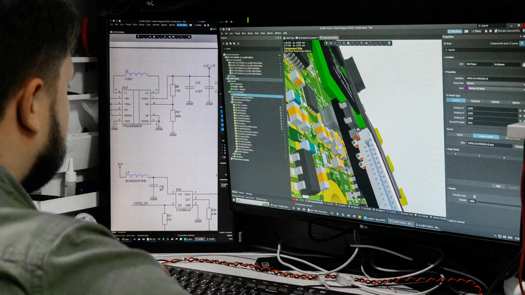 Engineer viewing electronic schematics and a circuit board model on two monitors