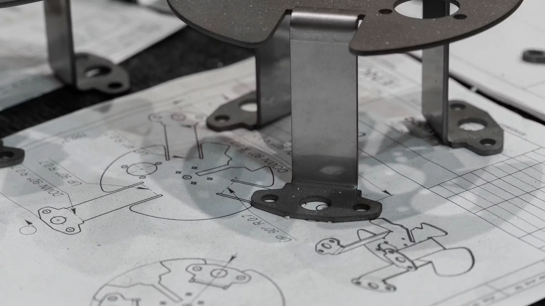 Fabricated metal brackets resting on a mechanical drawing
